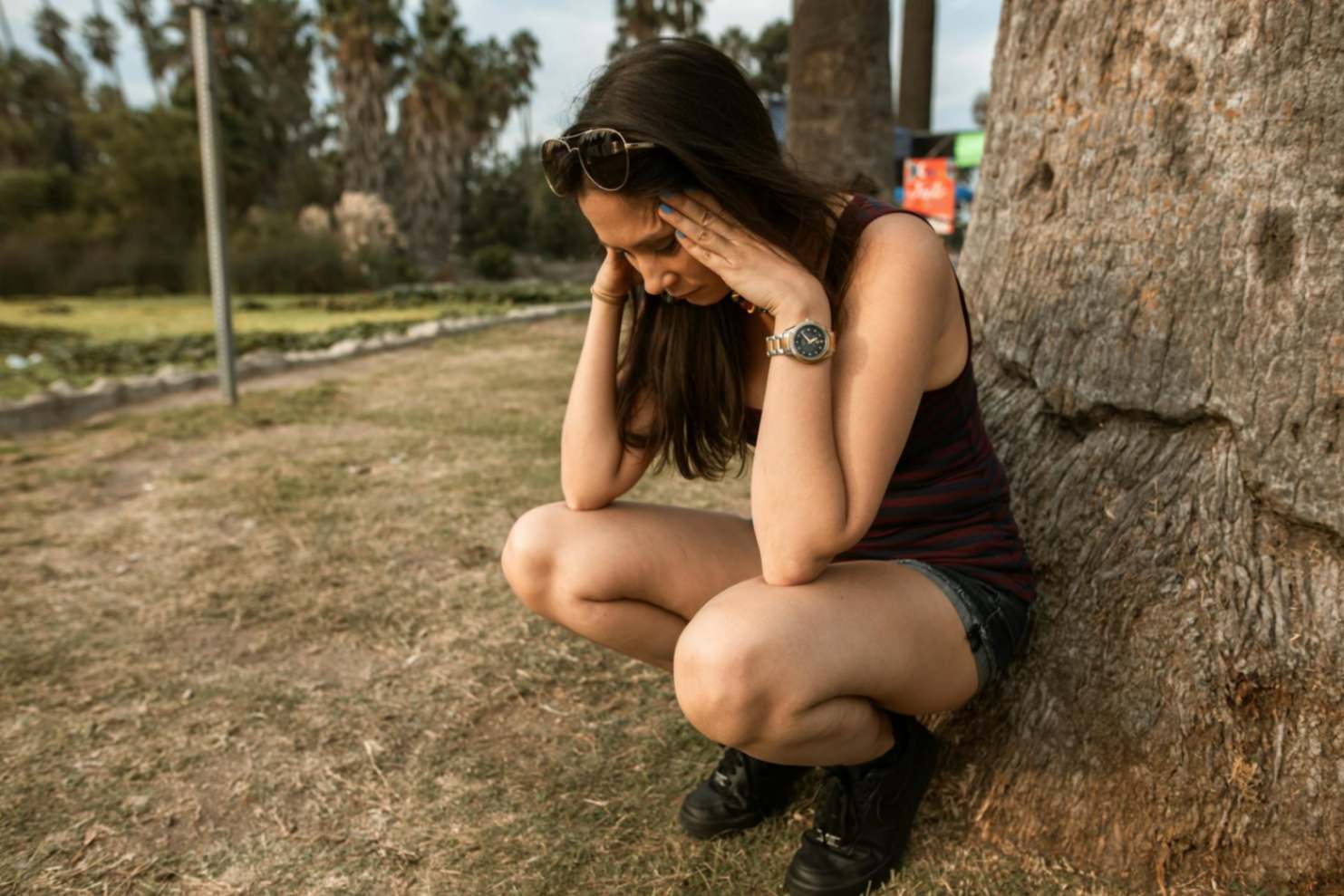Mujer agachada tocándose la cabeza